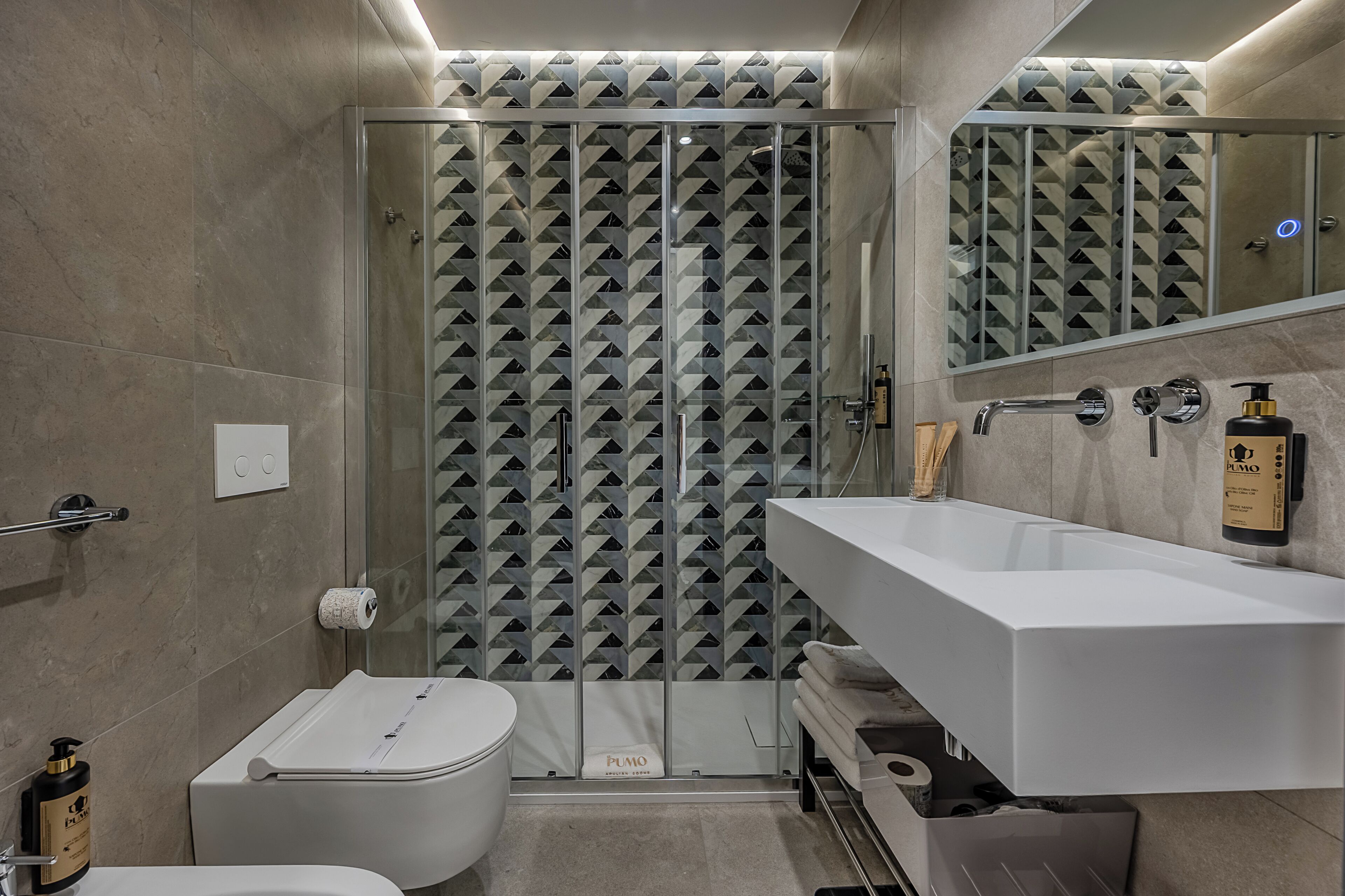 Un bagno moderno con box doccia in vetro, lavandino bianco e water.
