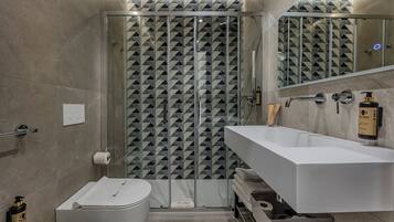 Un bagno moderno con box doccia in vetro, lavandino bianco e water.