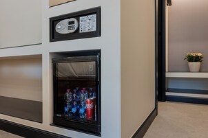 A minibar with a refrigerator containing bottled water and a can of Coca-Cola.