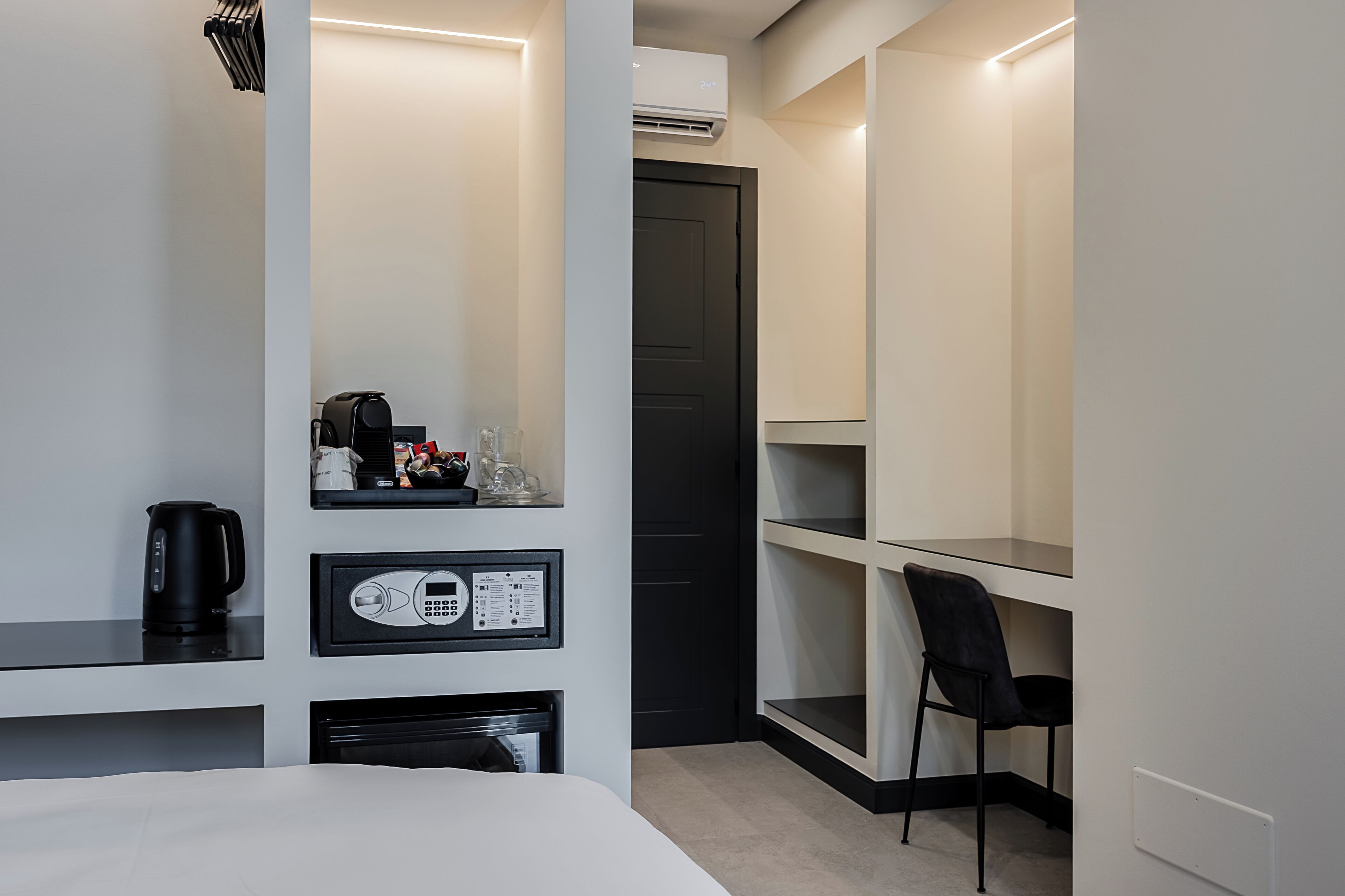 A hotel room with a bed, a desk, a chair, and a wardrobe.
