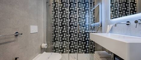 Ein modernes Badezimmer mit einer Duschkabine aus Glas, einem weißen Waschbecken und einer Toilette.