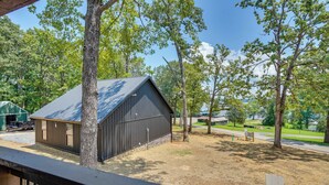 A building with a metal roof, surrounded by trees and a clear sky. - Family & Pet Friendly! Murray Cabin w/ Lake Access (Murray)