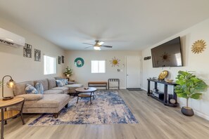 A living room with a sectional sofa, a coffee table, a TV, a ceiling fan, and a potted plant. - Stylish Maricopa Cottage w/ Mtn Views & Grill! (Maricopa)
