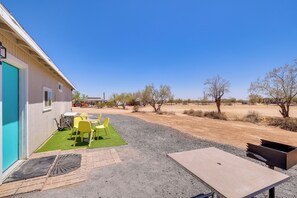 A building with a patio area featuring a table and chairs, a small garden, and a gravel path.