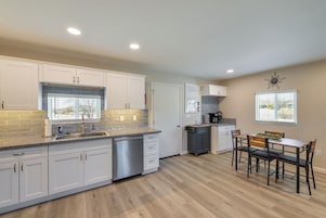 A modern kitchen with white cabinets, a granite countertop, and a built-in dishwasher.