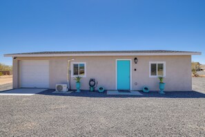 A single-story building with a garage, a turquoise door, and two potted plants.