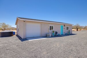 A single-story building with a garage, a small porch with potted plants, and a clear sky.
