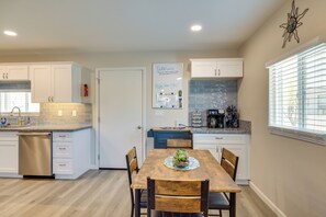 Una cocina moderna con armarios blancos, una mesa de comedor de madera y una isla de cocina.
