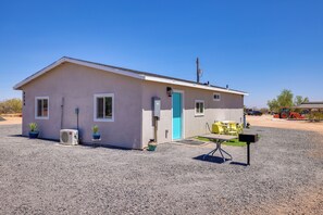 A single-story building with a flat roof, a front door, and a small porch area with outdoor seating.
