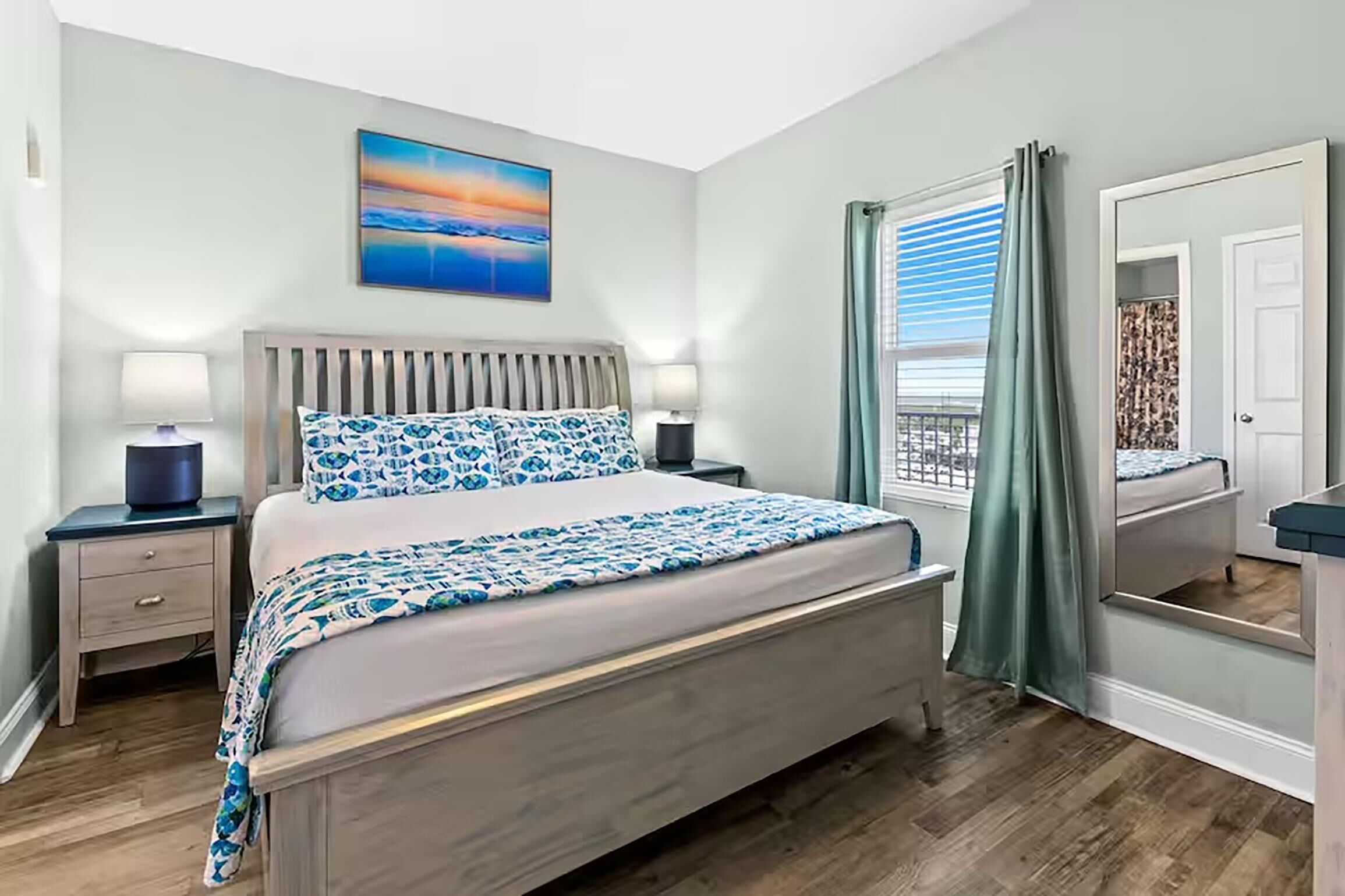 A bedroom with a bed, bedside tables, a nightstand, a window with curtains, and a painting on the wall.