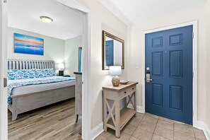 A bedroom with a bed, a bedside table, a lamp, and a painting on the wall. - Laketown Wharf 1817 (Panama City Beach)