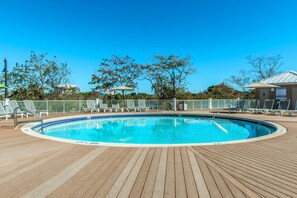 A wooden deck with a pool, lounge chairs, and a fenced area. - Laketown Wharf 1817 (Panama City Beach)