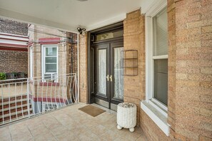 A brick building with a gated entrance, a door with a decorative glass panel, and a small white planter on the ground. - Near NYC Transit! Modern Gateway Region Apt (West New York)