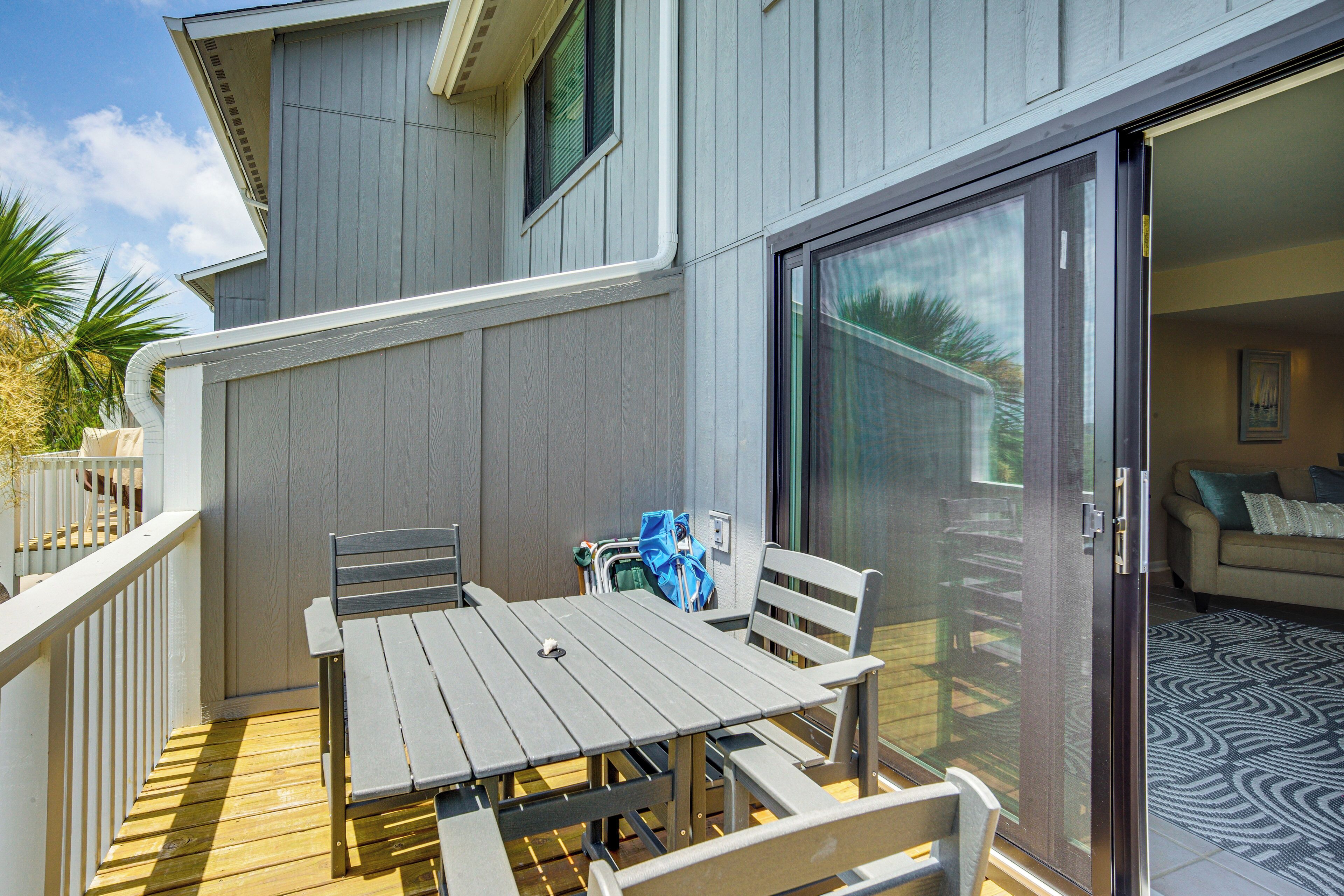 Une terrasse extérieure couverte, dotée d’une table et de chaises, une porte-fenêtre coulissante donnant sur un espace intérieur et une terrasse en bois.
