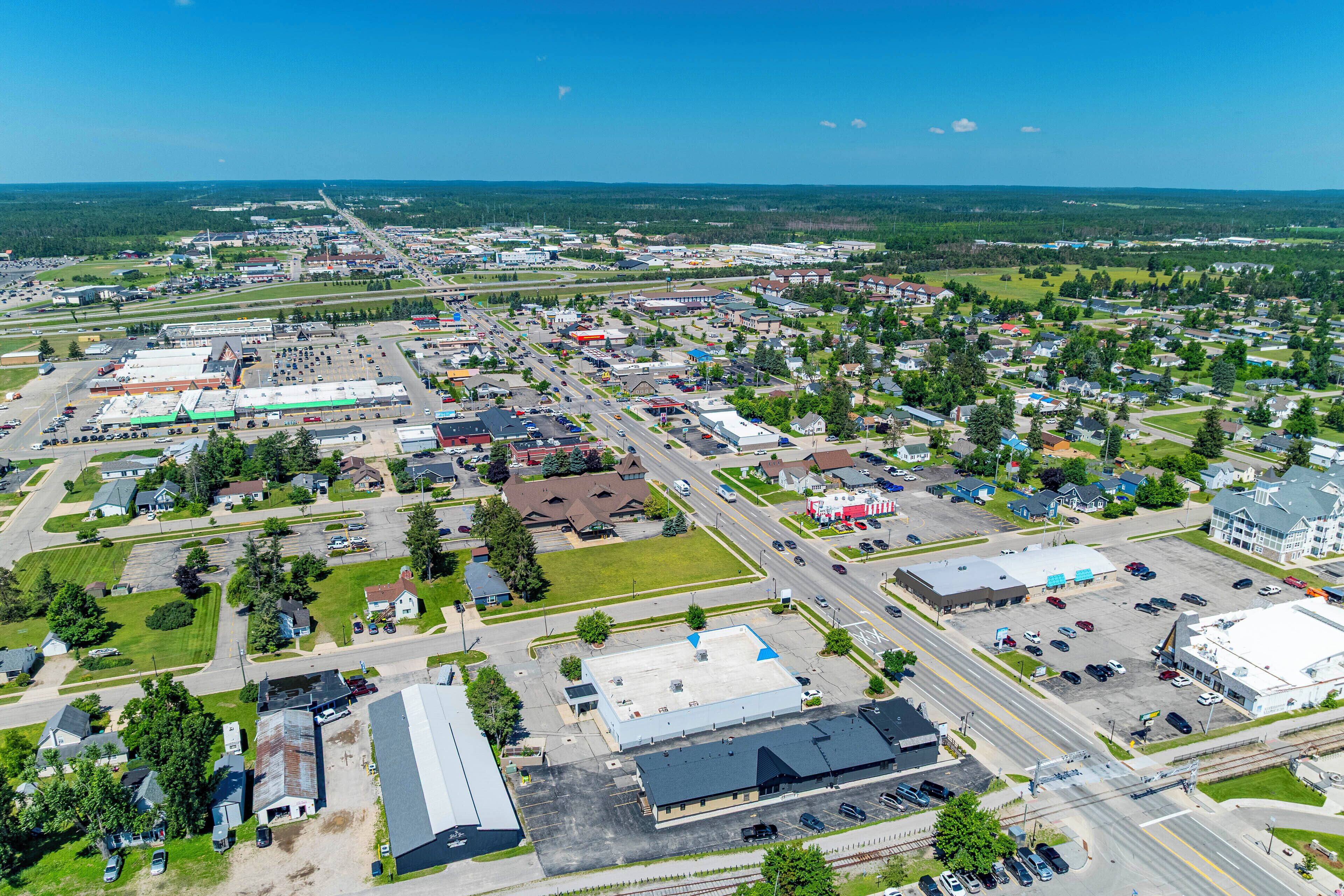 An aerial view of a town with a mix of commercial and residential buildings, roads, and green spaces.