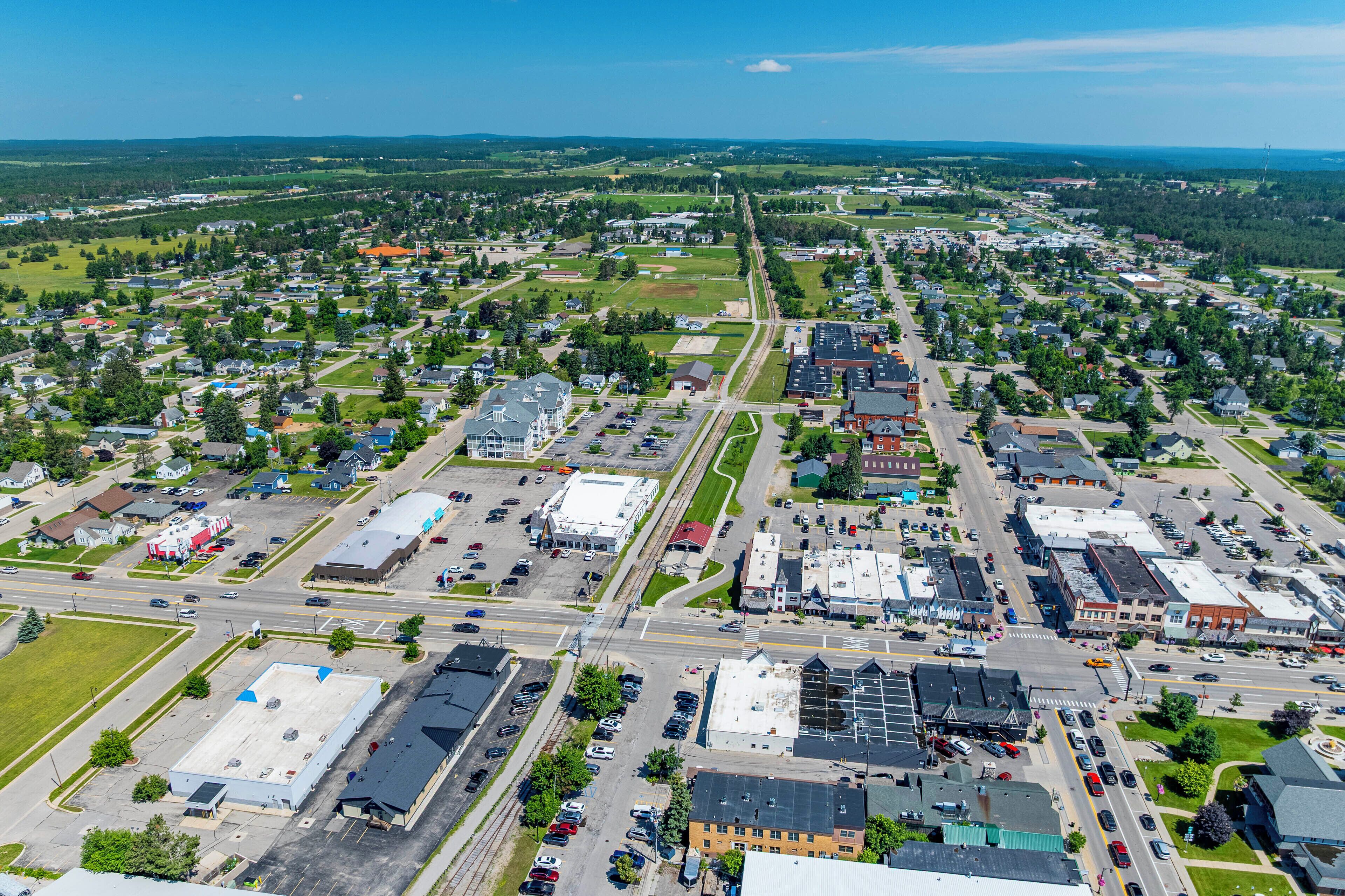 An aerial view of a town with a mix of residential and commercial buildings, roads, and green spaces.