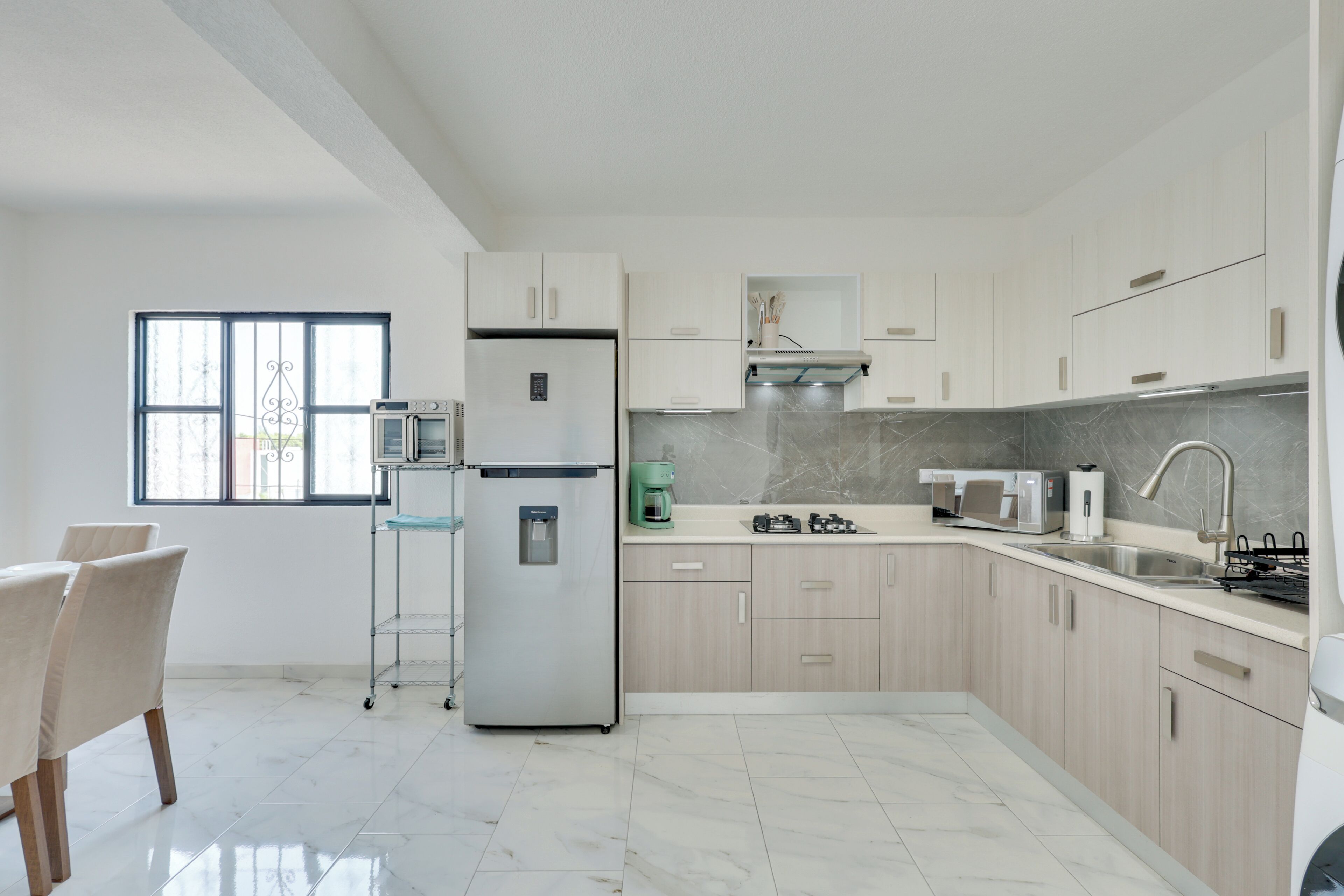 A modern kitchen with a refrigerator, stove, sink, and a window.