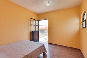 A room with a bed, a door leading outside, and a window.