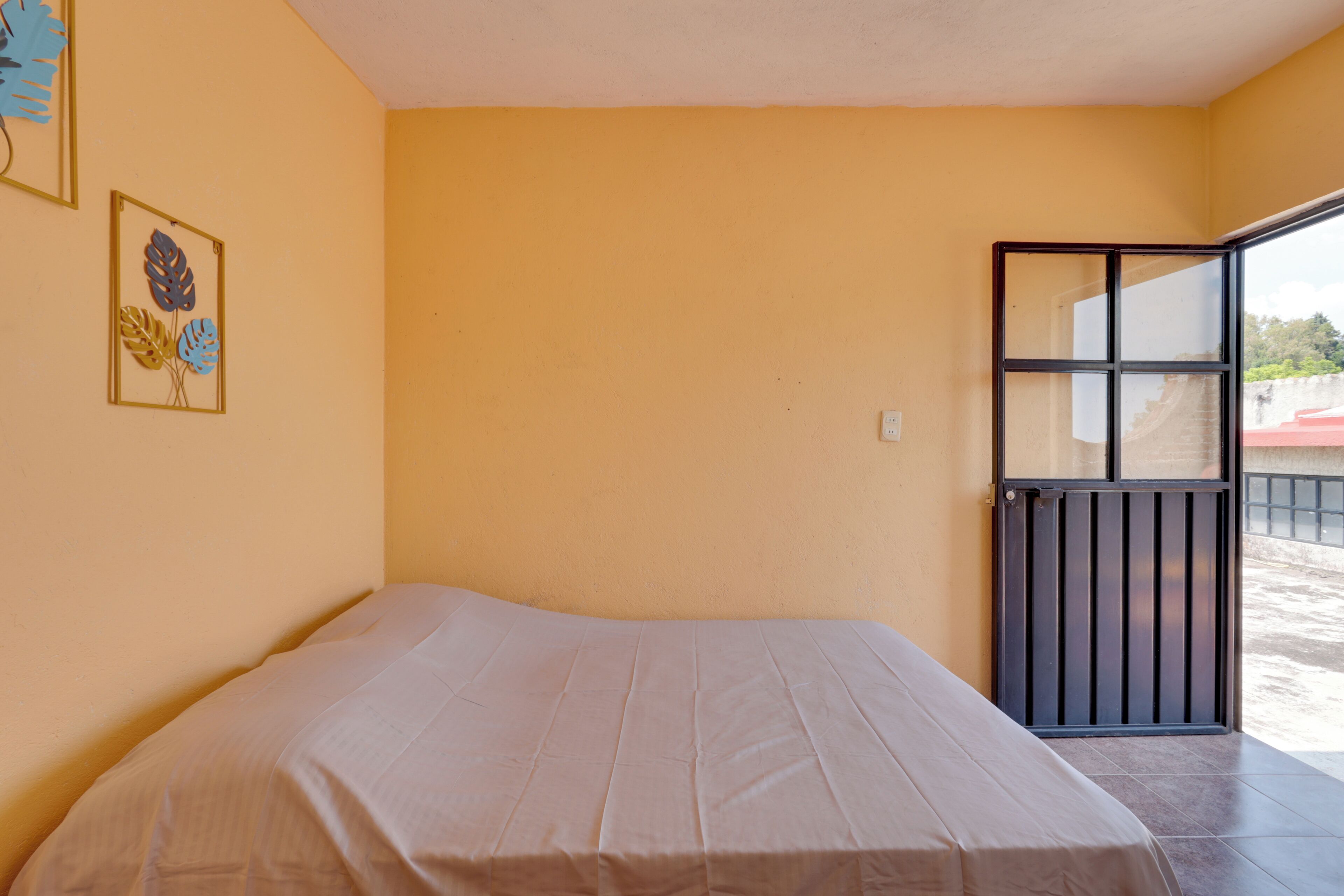 Una habitación con cama, puerta y ventana.