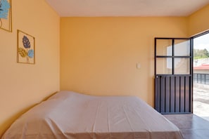 A room with a bed, a door, and a window.