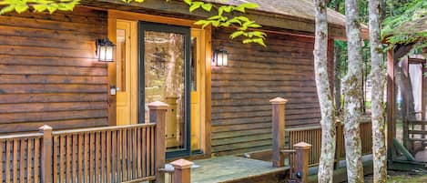 A wooden cabin with a porch, a door, and two lantern-style lights.