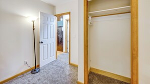 A hallway with a white door, a wooden closet with a hanging rod, and a floor lamp. - Near Beach & Trails! Lake Winnipesaukee Cabin (Moultonborough)