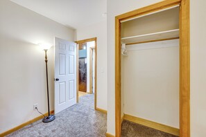 Ein Flur mit einer weißen Tür, einem Holzschrank mit Kleiderstange und einer Stehlampe.