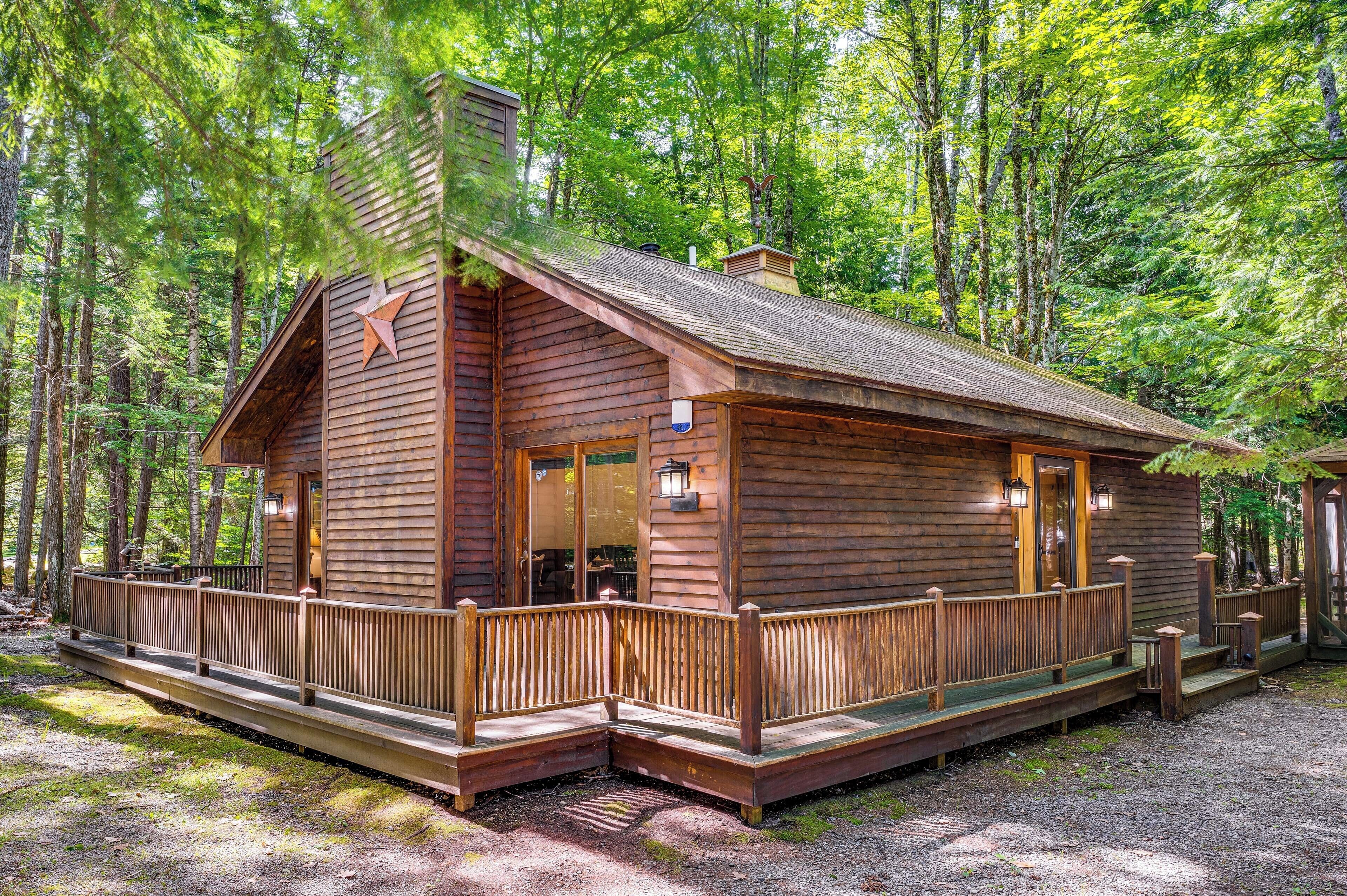 Eine Holzhütte mit einer Terrasse, umgeben von Bäumen.