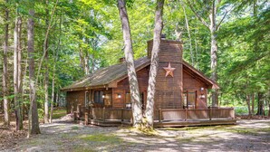 A rustic cabin with a porch, surrounded by tall trees. - Near Beach & Trails! Lake Winnipesaukee Cabin (Moultonborough)