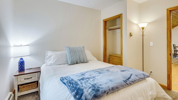 A bedroom with a bed, bedside table, lamp, and a mirror. - Near Beach & Trails! Lake Winnipesaukee Cabin (Moultonborough)