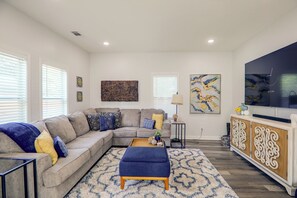 A modern living room with a sectional sofa, a coffee table, and a flat-screen TV.
