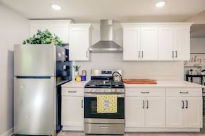 A modern kitchen with white cabinetry, a stainless steel refrigerator, a gas stove, and an oven.