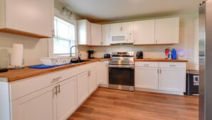 Una cucina moderna con pensili bianchi, un forno in acciaio inossidabile e un microonde.