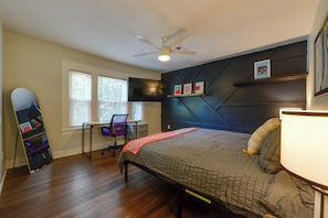 A bedroom with a bed, a desk with a chair, a ceiling fan, and a TV mounted on the wall. - 1 Mi to Uncg & Dtwn! Group Retreat w/ Private Yard (Greensboro)