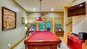 A pool table in a room with a billiards-themed wall art, a television mounted on the wall, and a staircase leading to another level. - Walk to Blue Ridge Parkway! Family Home w/ Hot Tub (Blowing Rock)