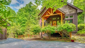 A wooden cabin with a porch, surrounded by lush greenery. - Walk to Blue Ridge Parkway! Family Home w/ Hot Tub (Blowing Rock)