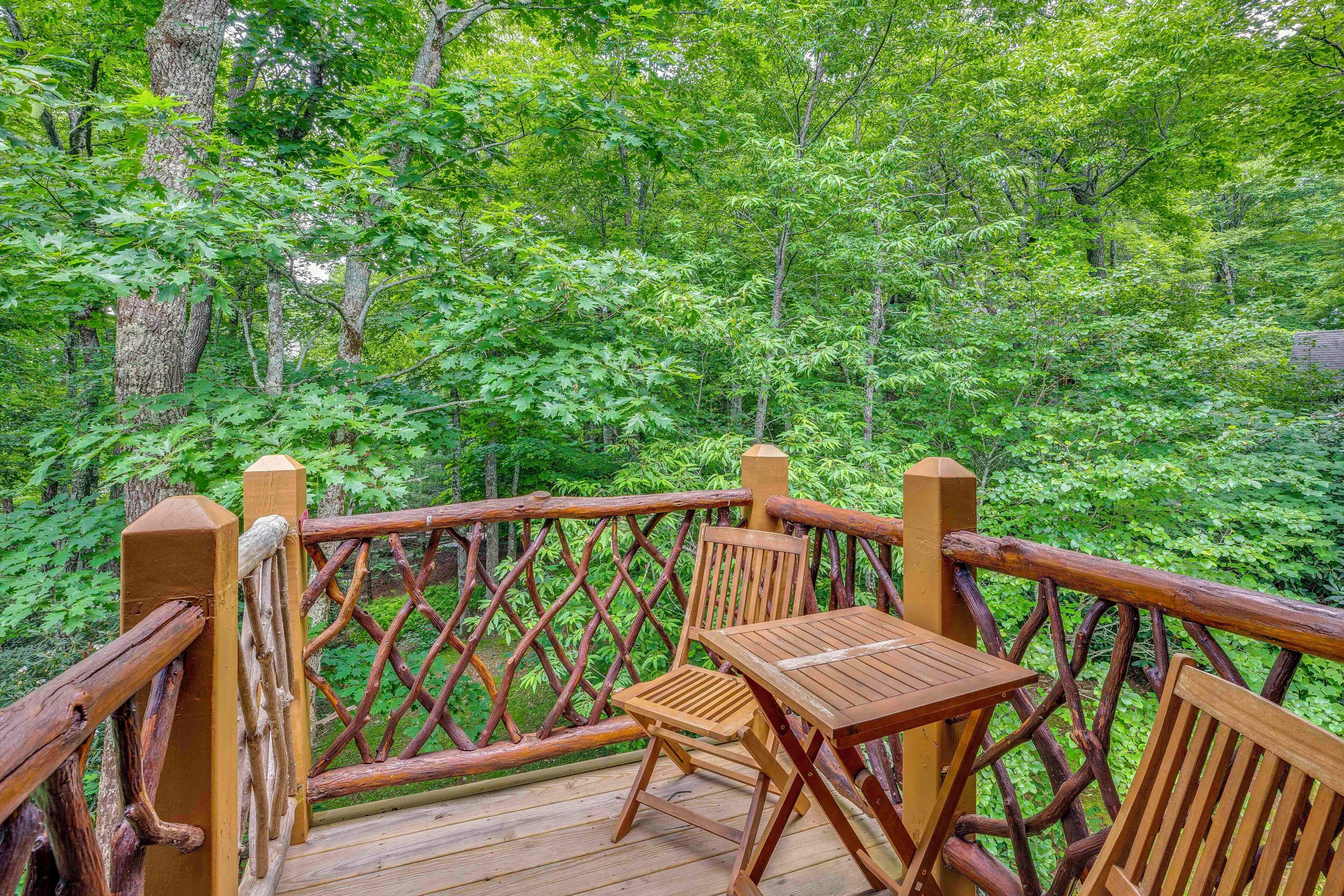 A wooden deck with a table and chairs overlooking a forest.