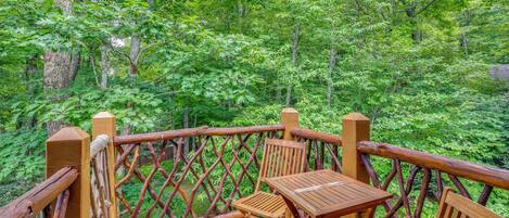 A wooden deck with a table and chairs overlooking a forest.