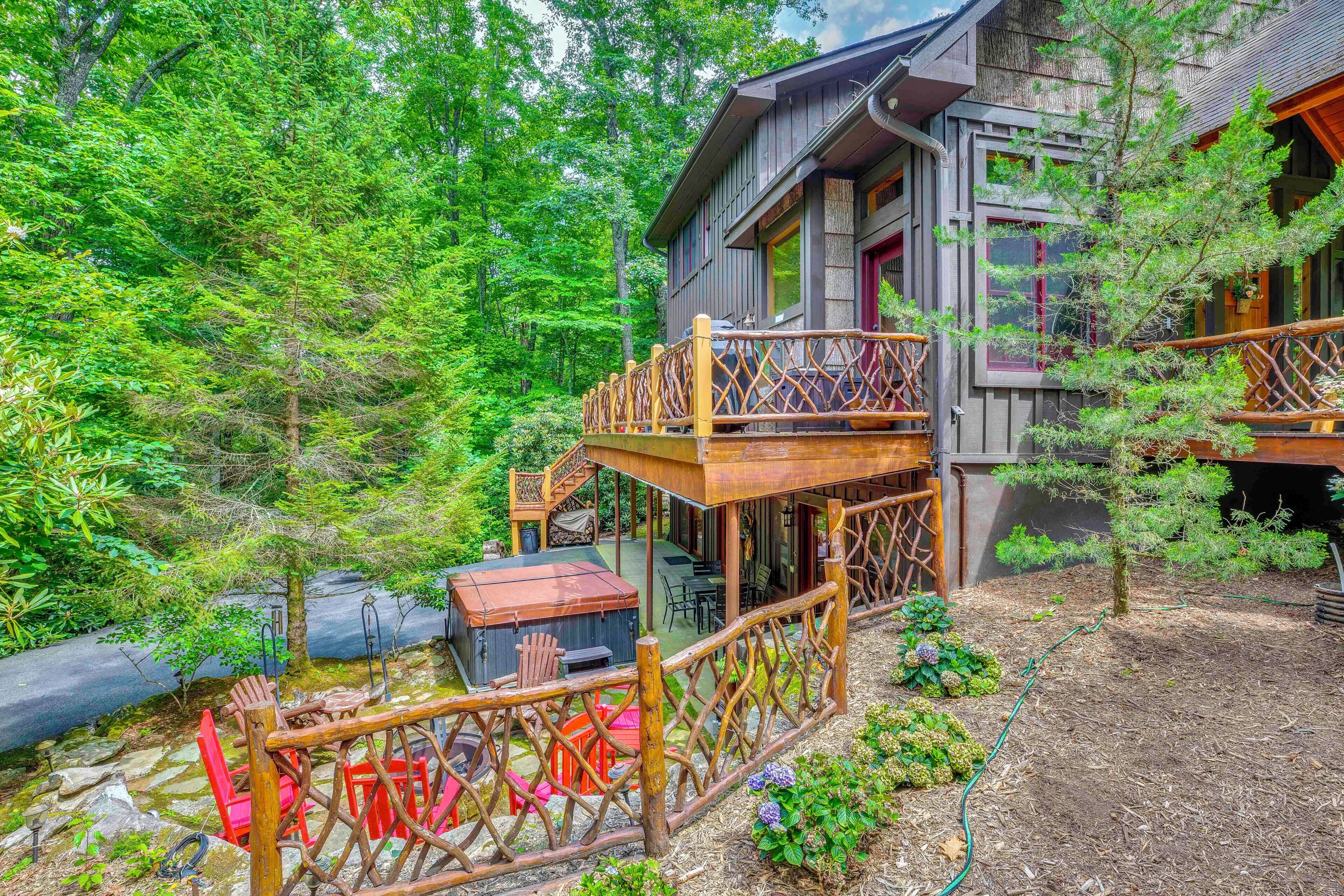 A cabin with a wooden deck, outdoor seating, and a hot tub.