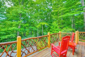 A wooden deck with a railing, a red chair, and a table. - Walk to Blue Ridge Parkway! Family Home w/ Hot Tub (Blowing Rock)