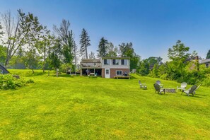 A two-story house with a deck and a grassy yard. - Waterfront Getaway: Sunroom, 2 Decks, Golf Course (Wolcott)