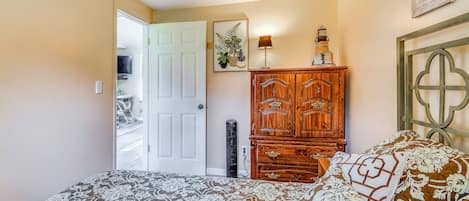 A bedroom with a bed, a wooden wardrobe, a door, and a wall-mounted picture.