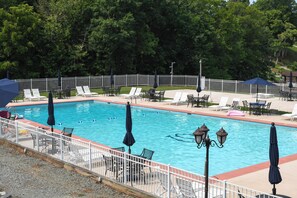 A rectangular swimming pool with a white fence, surrounded by lounge chairs and umbrellas. - Pool, Lake & Sunsets in Front of the Condo Patio (Moneta)