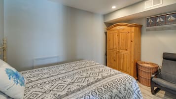A bedroom with a bed, a wardrobe, a chair, and a wall-mounted shelf with decorative items.
