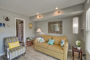 A living room with a sofa, armchair, and a lamp. There is a door leading to another room. - Pool, Lake & Sunsets in Front of the Condo Patio (Moneta)