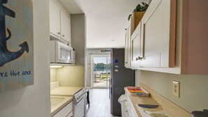 Una cucina piccola con mobili bianchi, un forno a microonde e un frigorifero.