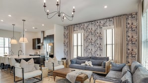 A modern living room with a grey sofa, a coffee table, and a dining area with a kitchen in the background. - Pool Access! Centrally Located ATL Escape w/ Deck (Atlanta)