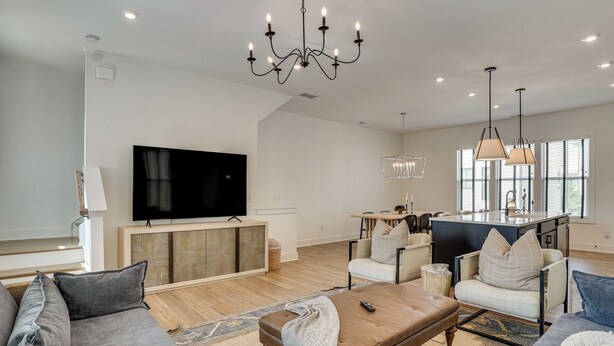A spacious living room with a large flat-screen TV, comfortable seating, a wooden coffee table, and a chandelier. - Pool Access! Centrally Located ATL Escape w/ Deck (Atlanta)