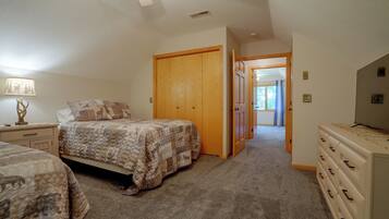 A bedroom with two beds, a dresser, and a door leading to another room.