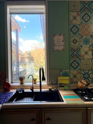 Una cocina con ventana, un lavamanos, un grifo y una estufa.